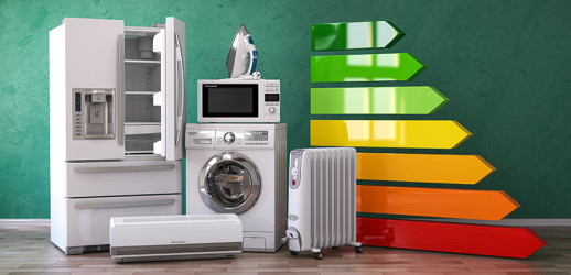 Verschillende witte elektronische apparaten van strijkijzers tot koelkasten staan ​​voor een groene muur. Rechts achter zie je de pijlen van de energieklassen.