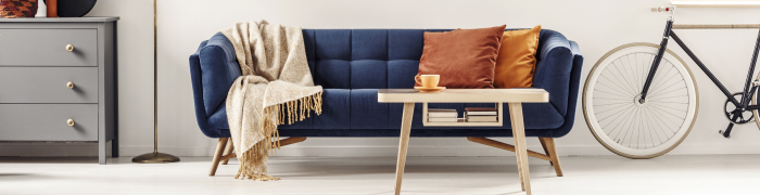 Donkerblauwe sofa met salontafel van licht hout en gezellig huistextiel
