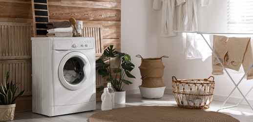 Een bijkeuken in natuurlijke tinten. Een wasmachine, een wasmand en een droogrek zijn te zien.
